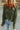 a woman wearing a green sweater and blue jeans